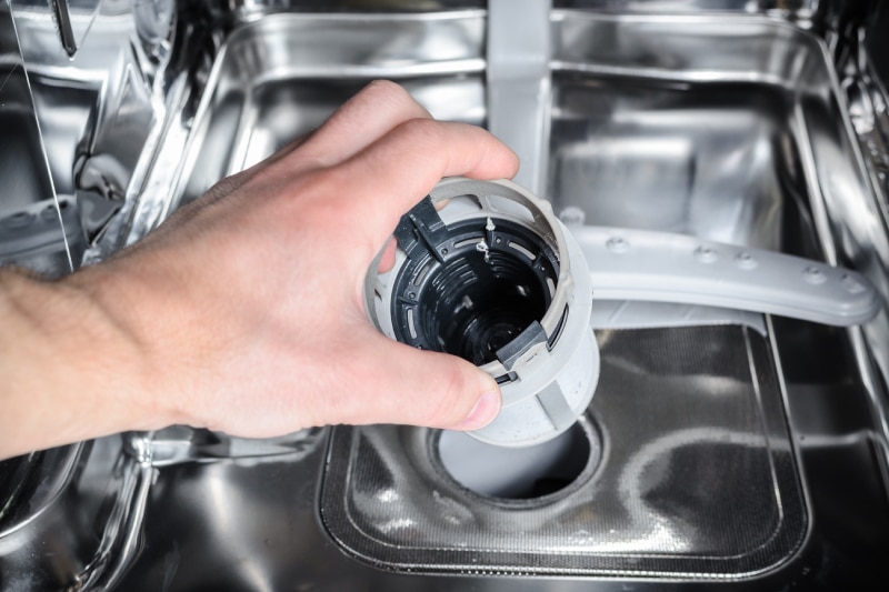 man cleans the filter in the dishwasher