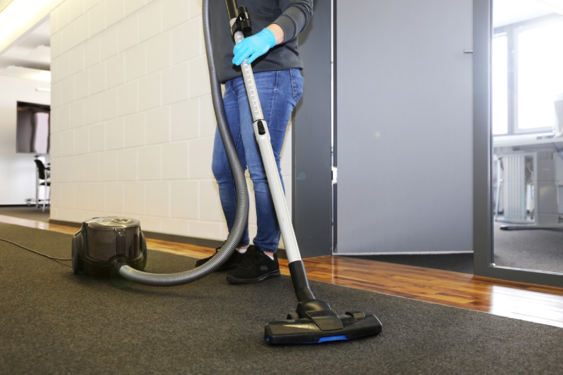 Cleaner vacuums the corridor of an office