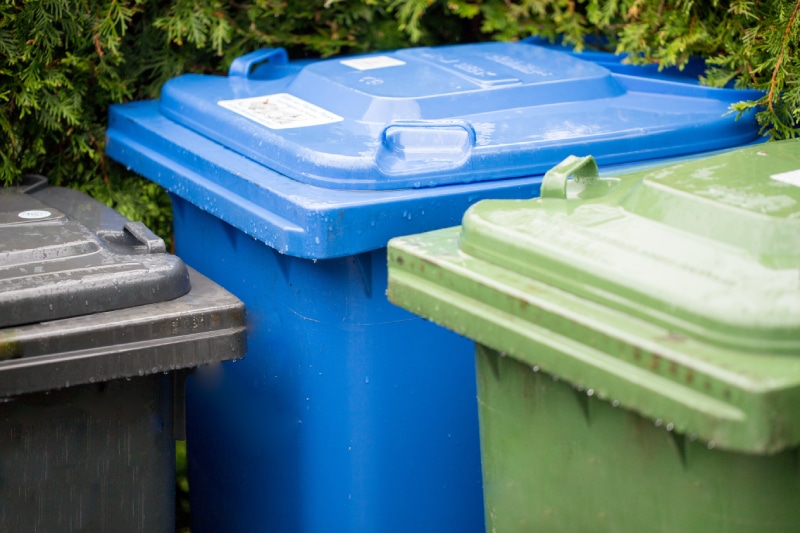 black, blue, and green trash cans outside