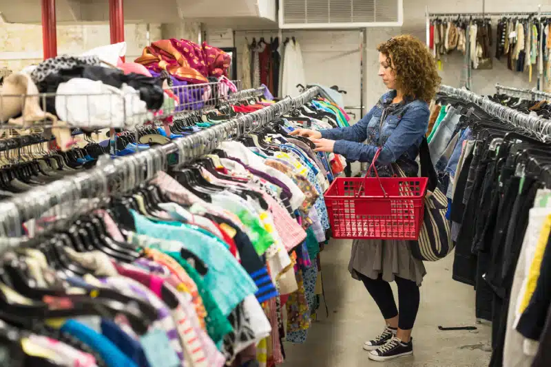 Woman looking through a rack of clothing at a thrift store